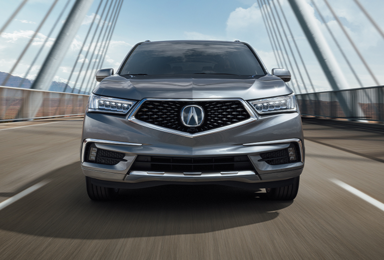 2019 Acura MDX Advance in Modern Steel Metallic front driving on a suspension bridge (Premium Performance SUV).
